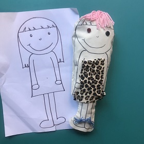 Drawing of doll in black pen with replica placed ontop of drawing made in soft sculpture of doll , pink hair, leopard dress, material face with features drawn on in black pen