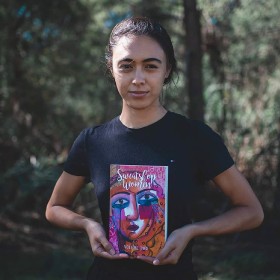 Sydney Writers Festival promo image photo of Winnie Dunn writer holding Sweatshop Women book, bush in background