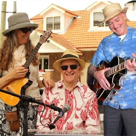 Photo of the Jazz West Combo, three musicians wearing hats pose candidly for a photo, one holds a ukelele one plays at a keyboard and the other holds an acoustic guitar
