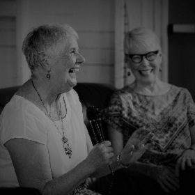 Black and white photo of two older women laughing and smiling expressively
