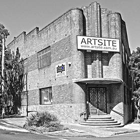 Black and white photograph of the Artsite Gallery building taken from across the street showing the gallery entrance, building is made of brick and looks like an art deco design