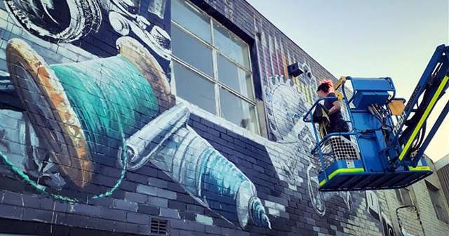 Artist Camilla Lawson paints a mural from a crane