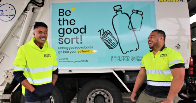 Two laughing men standing in front of recycling truck