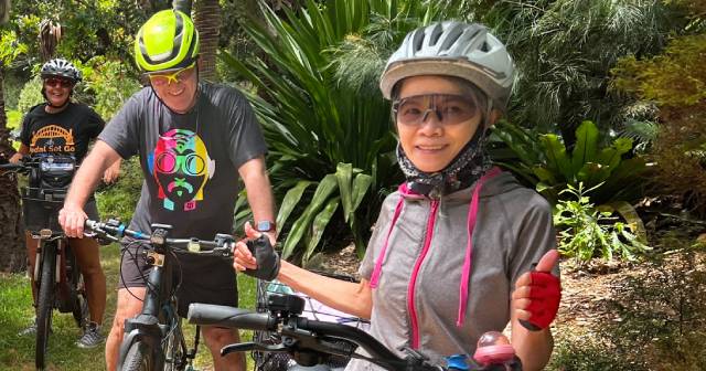 Three women on bikes in a natural setting. 