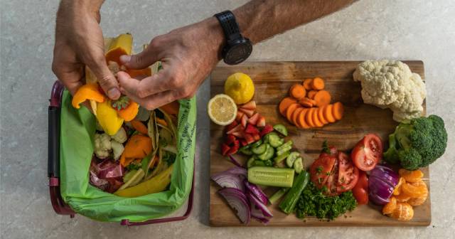 Hand putting food scraps into food recycling bin