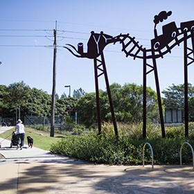 Tall sculptures beside a walking path through a park