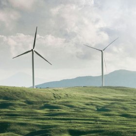 Two wind turbines on rolling green hills