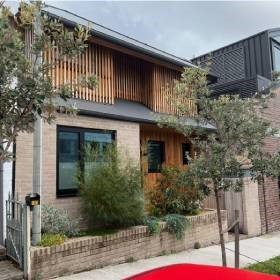 Two story suburban house with wood panels and bushes in garden