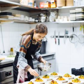 Woman leans over bench adjusting food on a plate