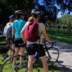 Three women and their bikes standing by the Cooks River