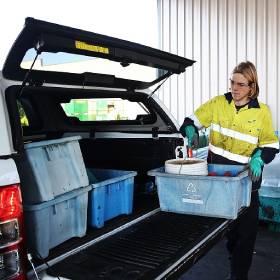 Man in yellow vest taking boxes from car boot