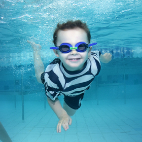 Little boy swimming underwater wearing goggles and smiling