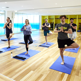Group of people standing holding yoga pose in a studio