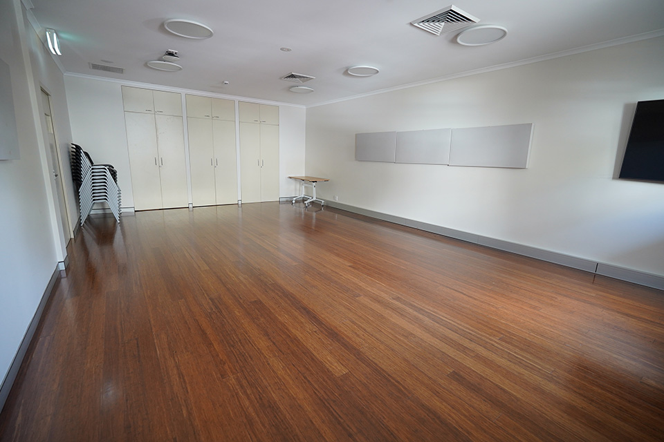 A plainly-decorated community centre activity room with a polished wood floor.