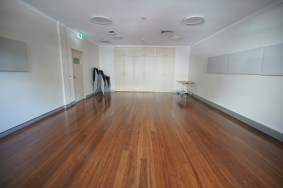 A plainly-decorated community centre activity room with a polished wood floor.