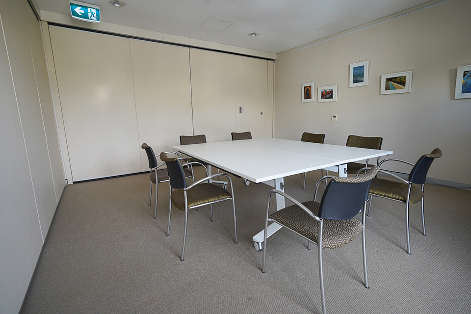 A meeting room with eight chairs arranged around a central table.
