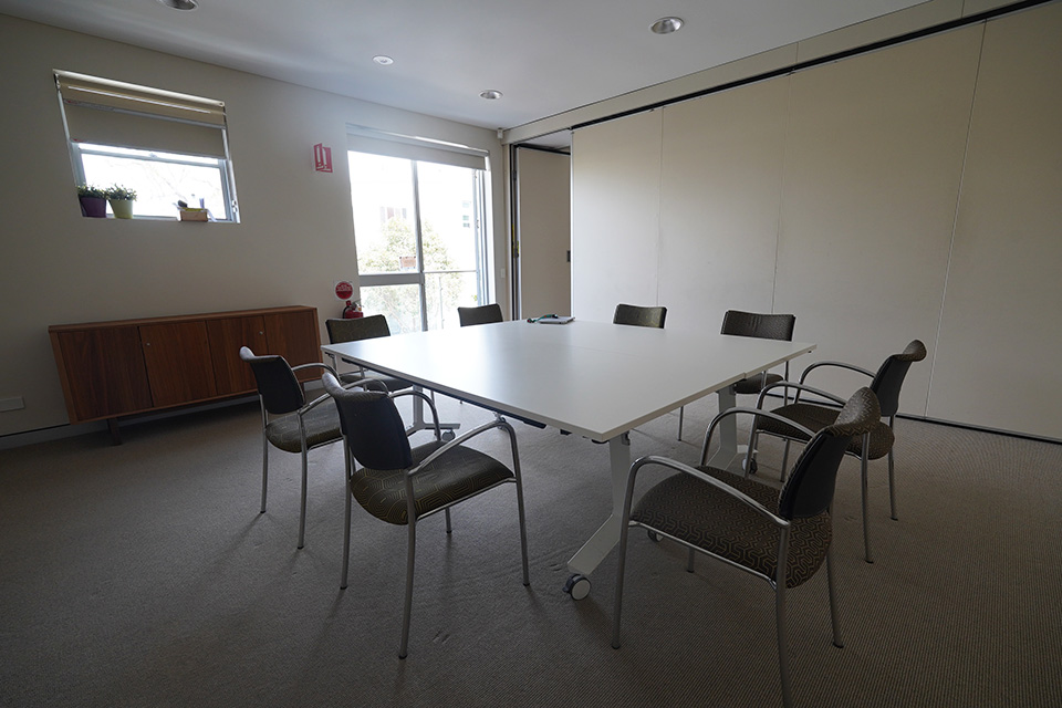 A meeting room with eight chairs arranged around a central table.
