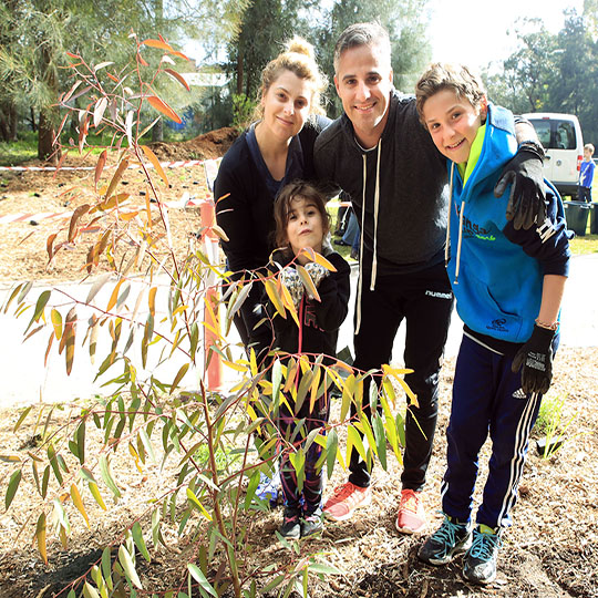 family standing behind a small sapling with green leaves \