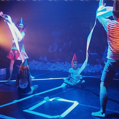 children wearing party hats playing with streamers under UV lights