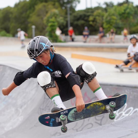 Close up image of a skateboarder in a skate park getting some air and grabbing the board