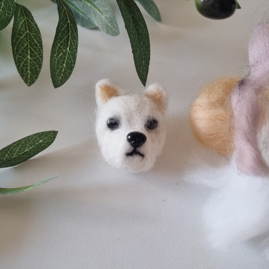 cute white dogs head made out of felt surrounded by leaves