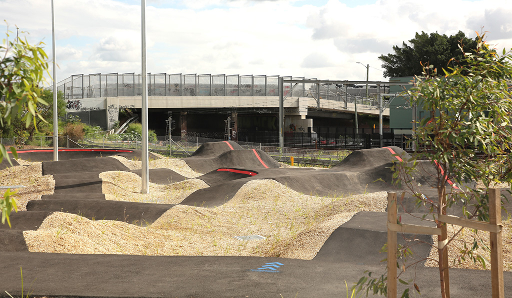 An undulating BMX track with a road bridge in the background.