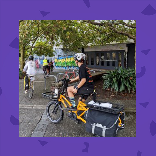 Woman outdoors with a bike. Image surrounded by a purple frame.