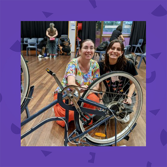 Woman outdoors with a bike. Image surrounded by a purple frame.