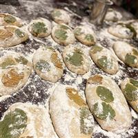 Flat breads on a floured surface with a vine leaf on top