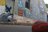 Wilson basketball in focus bottom right corner with background of sandstone and graffiti wall across road blurred