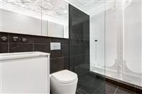Apartment bathroom interior with black tiles white and mirror cabinetry and white walls and ceiling with heritage feature framing and textures