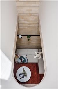 Aerial interior image looking down through curved skylight to living area with grey lounge and red rug