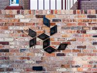 Warm coloured brick wall with various small parallelogram bronze interpretive tiles
