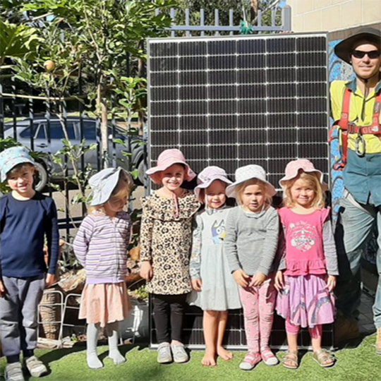 Children standing in front of a solar panel