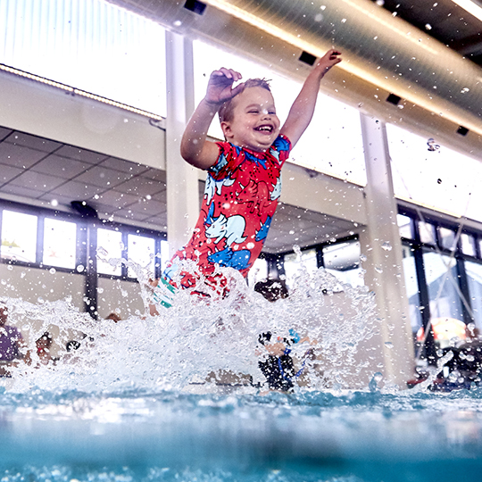 Boy jumping and splashing into pool 