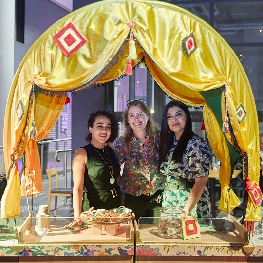 Photo of the My Plate, Your Plate Cart, the photo shows the silky arch awning of the cart that has been decorated, inside the awning are Erica, Raffaela and Elham