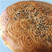 Photo of Afghani bread, disc like shape of golden bread with pretty design made across the bread in pricks and black and white sesame seeds
