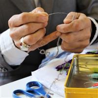 Artist Sayd threads a homemade tapestry needle with wool