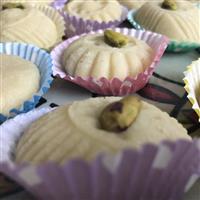 Syrain raw almond biscuit with pistachip in centre, off white coloured biscuit with pretty pattern similar to a jelly mold with lines 