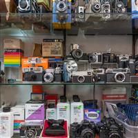 A variety of vintage cameras and photo lab chemicals displayed on shelves