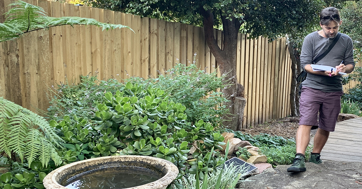 Man taking notes around a garden