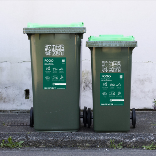 Two green lid bins side by side with a large rectangular green sticker on the front