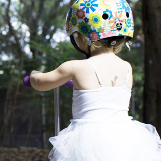 Little girl on scooter with flowered helmet 