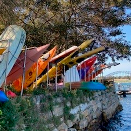 Various small boats stored vertically on a harbour foreshore.