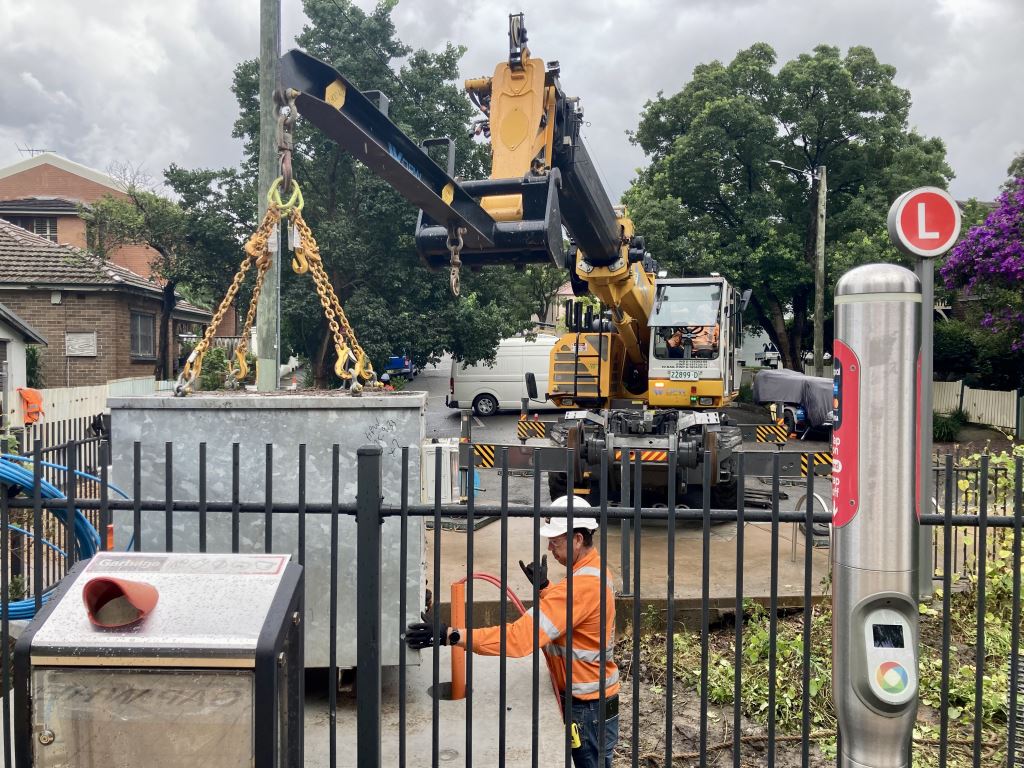 Workers relocating an existing signal box at Waratah Mills light rail station