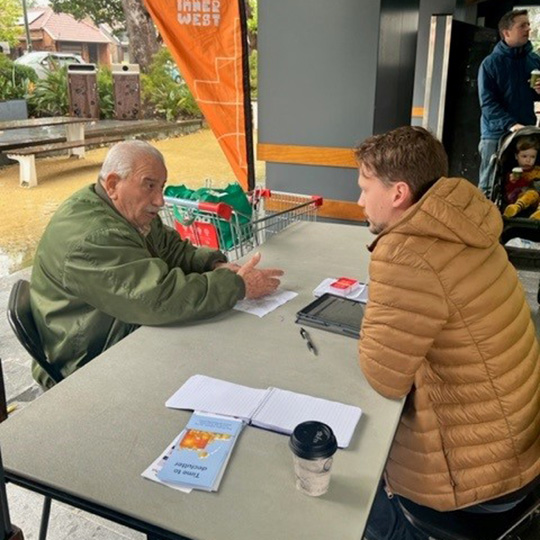 Council officer assisting elderly resident over a table