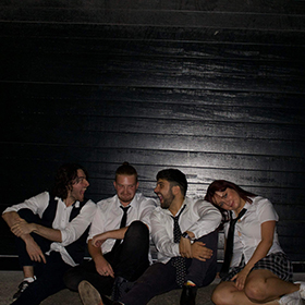 three boys and a girl wearing school uniforms sit on the floor