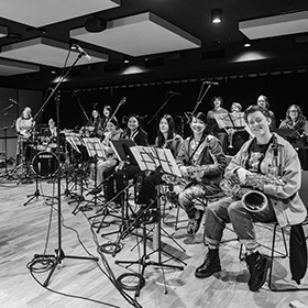 a black and white photo of an orchestra of young women smiling at the camera