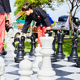 A boy in red pants plays giant chess