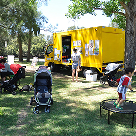 A yellow truck parked in a park